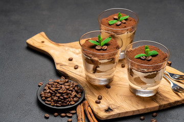 Classic tiramisu dessert with chocolate in a glass no wooden cutting boartd on dark concrete background