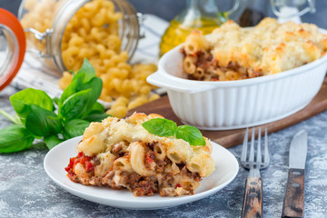 Macaroni casserole with ground beef, cheese and tomato on a white plate, horizontal
