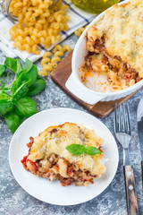 Macaroni casserole with ground beef, cheese and tomato on white plate, vertical,  top view