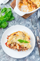 Macaroni casserole with ground beef, cheese and tomato on plate, vertical, top view