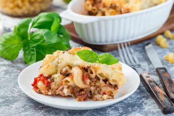 Macaroni casserole with ground beef, cheese and tomato on  white plate, horizontal, closeup