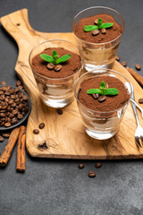 Classic tiramisu dessert with chocolate in a glass no wooden cutting boartd on dark concrete background