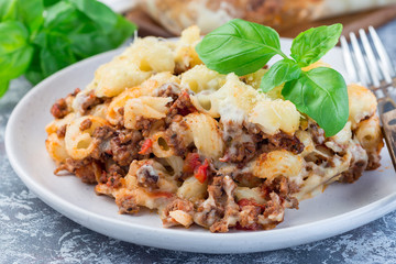 Macaroni casserole with ground beef, cheese and tomato on plate, horizontal, closeup