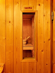 The door of a wooden sauna with a sauna bucket visible through the window.