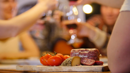 Sausage cheese and tomatoes on the table - friends having a party - cheers
