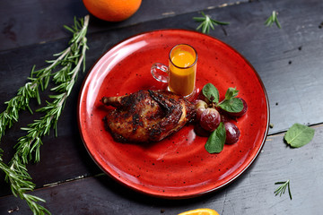 fried quail with grapes, mint and berry sauce, on a red plate