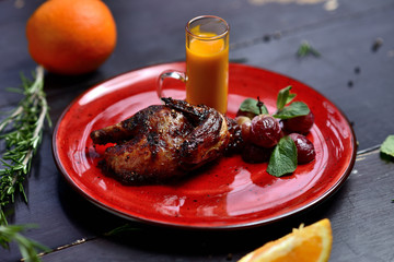 fried quail with grapes, mint and berry sauce, on a red plate
