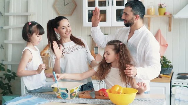 Happy family preparing food on kitchen, cutting vegetables, slow motion