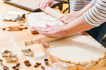 Home pastry cooking class. Cropped shot of woman teaching daughter how to roll dough in flour, make gingerbread biscuits.