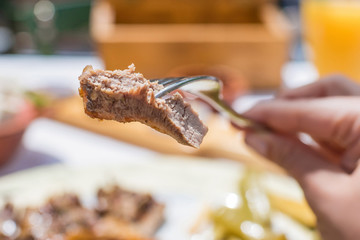 Sliced grilled lamb chops on a fork. Woman have a dinner in a greek tavern