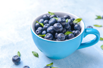 Cup with ripe blueberry on light background