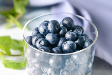 Glass container with ripe blueberry on table, closeup