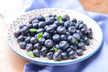 Plate with ripe blueberry on wooden background