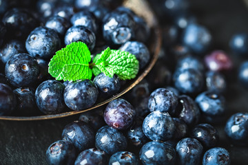 Juicy and fresh blueberries with green leaves on rustic table. Blueberry antioxidant. Concept for healthy eating and nutrition. Selective focus.