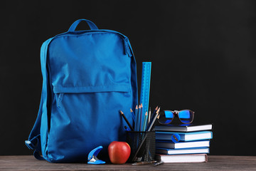 School backpack with stationery on table in classroom