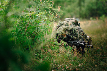 The soldier conducts reconnaissance. Airsoft player in position.