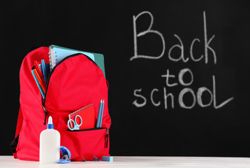 School backpack with stationery on table in classroom