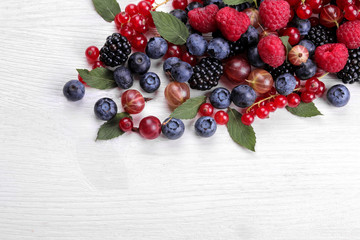 Delicious berries in a bowl, currants, blackberries, blueberries, raspberries on a white wooden table. place for text. top view. frame