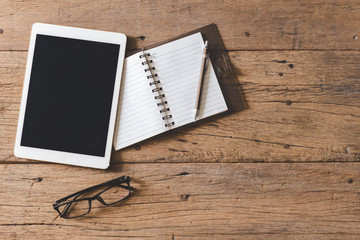 Top view of Pen, notebook, glasses, tablet on wooden table and copy space