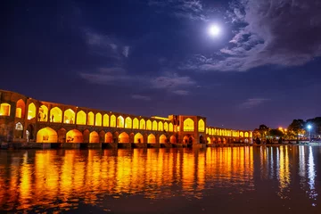 Rollo Khaju-Brücke Khaju Bridge over Zayandeh river is iluminated at dusk with lights and moon in sky, Serving as a dam as well