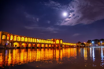 Photo sur Plexiglas Pont Khadjou Khaju Bridge over Zayandeh river is iluminated at dusk with lights and moon in sky, Serving as a dam as well