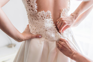 Bride getting dressed by her mother and bridesmaid