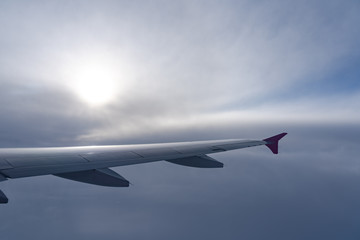 Fototapeta premium Up in the air, view of aircraft wing silhouette with dark blue sky horizon and cloud background in sunset time, viewed from airplane window