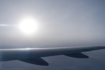 Up in the air, view of aircraft wing silhouette with dark blue sky horizon and cloud background in...