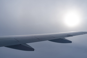 Up in the air, view of aircraft wing silhouette with dark blue sky horizon and cloud background in...