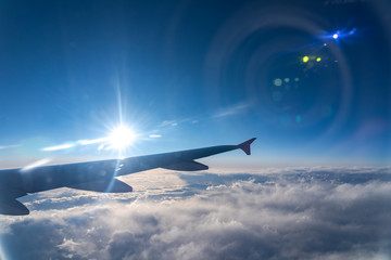 Up in the air, view of aircraft wing silhouette in dark blue sky horizon and cloud background in sunset time. viewed from airplane window, with a reflection camera lens
