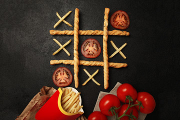 Game of tic tac toe of french fries and tomatoes. Choosing healthy vs unhealthy foods. Fit or fat...