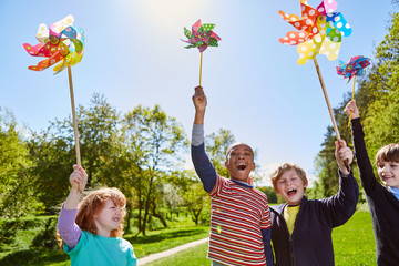 Gruppe Kinder spielt mit bunten Windrädern