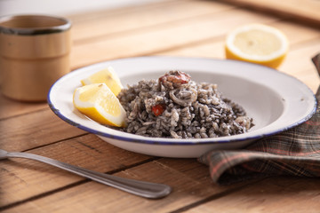 Plate of black rice with squid and prawns or Valencian black paella