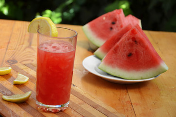Colorful tropical fresh watermelon smoothie summer drinks in the glasses on wood table background. Refreshing watermelon coсtail with slimon of green foliage. The concept of leisure, travel