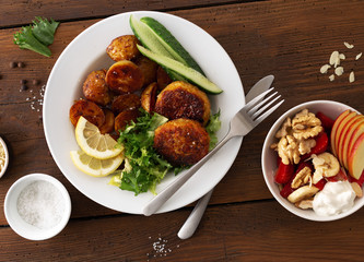 Dinner table with plate food. Fresh vegetarian cutlets with new potatoes and salad top view