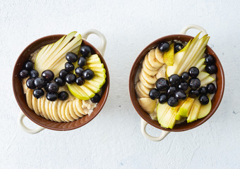 Plate with oatmeal and pear, apple, blueberry, banana on a white background top view. Breakfast table concept