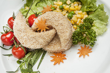 Breaded Chicken Breast. The decor of cherry tomatoes, corn, basil, lettuce. Still life, carrot decorative cut