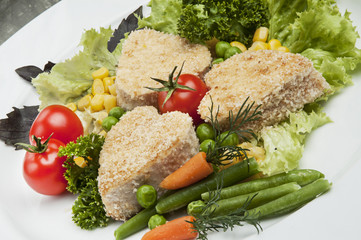 Breaded Chicken Breast. The decor of cherry tomatoes, corn, basil, lettuce. Still life, carrot decorative cut