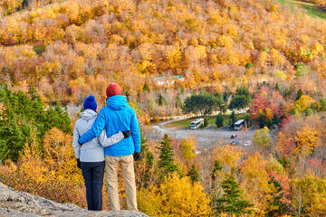 Couple hiking at Artist's Bluff in autumn. Fall colours in Franconia Notch State Park. White...