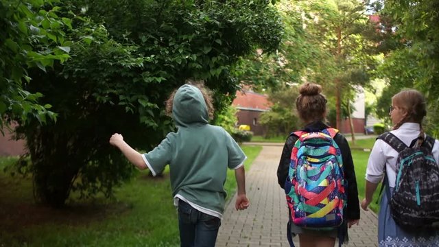The beginning of the summer holidays, the end of the school year. Children fun run out of school, waving backpacks over their heads