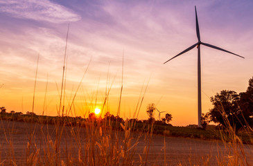 Wind turbines electric power generator on sunset sky at agriculture field
