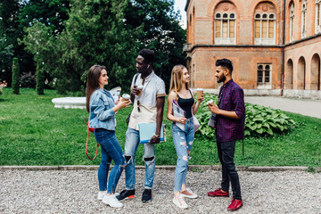 Fototapeta premium Summer, friendship, education and teenage concept - group of happy students with folders learning and drinking coffee at campus.
