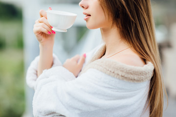 Close up photo. Woman lips drink coffee. Early morning with cup. Summer terrace on resort.