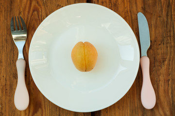 Ripe fresh apricot fruits on a white plate on the wooden background. Copy space, delisious healthy food.