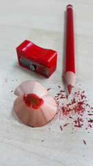 Red pencil and sharpener, isolated on wood background.