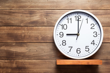 wall clock at shelf on wooden background