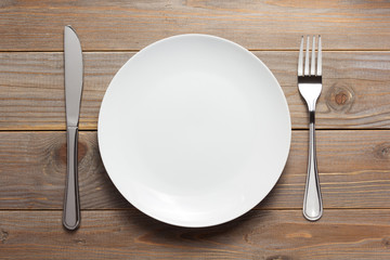 plate, knife and fork at wooden  background