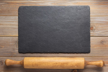 slate stone and rolling pin at rustic wooden background