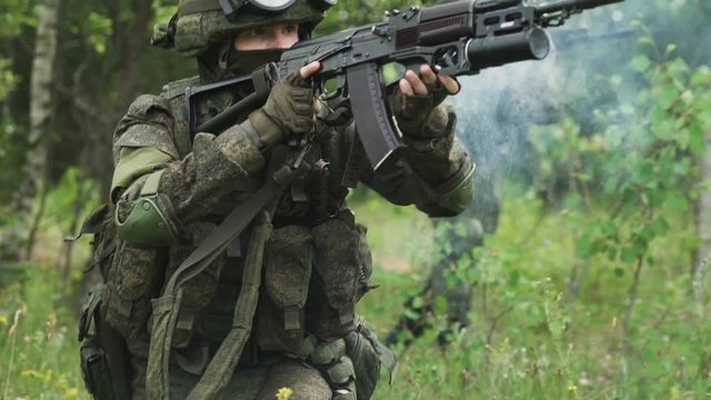 Soldier in camouflage fires a grenade launcher in assault rifle, military action in forest, soldiers on mission.