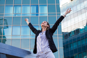 businesswoman in a business suit, exulted by happiness after finishing the deal, in the background skyscrapers. Concept of: business, technology, economy and work and success